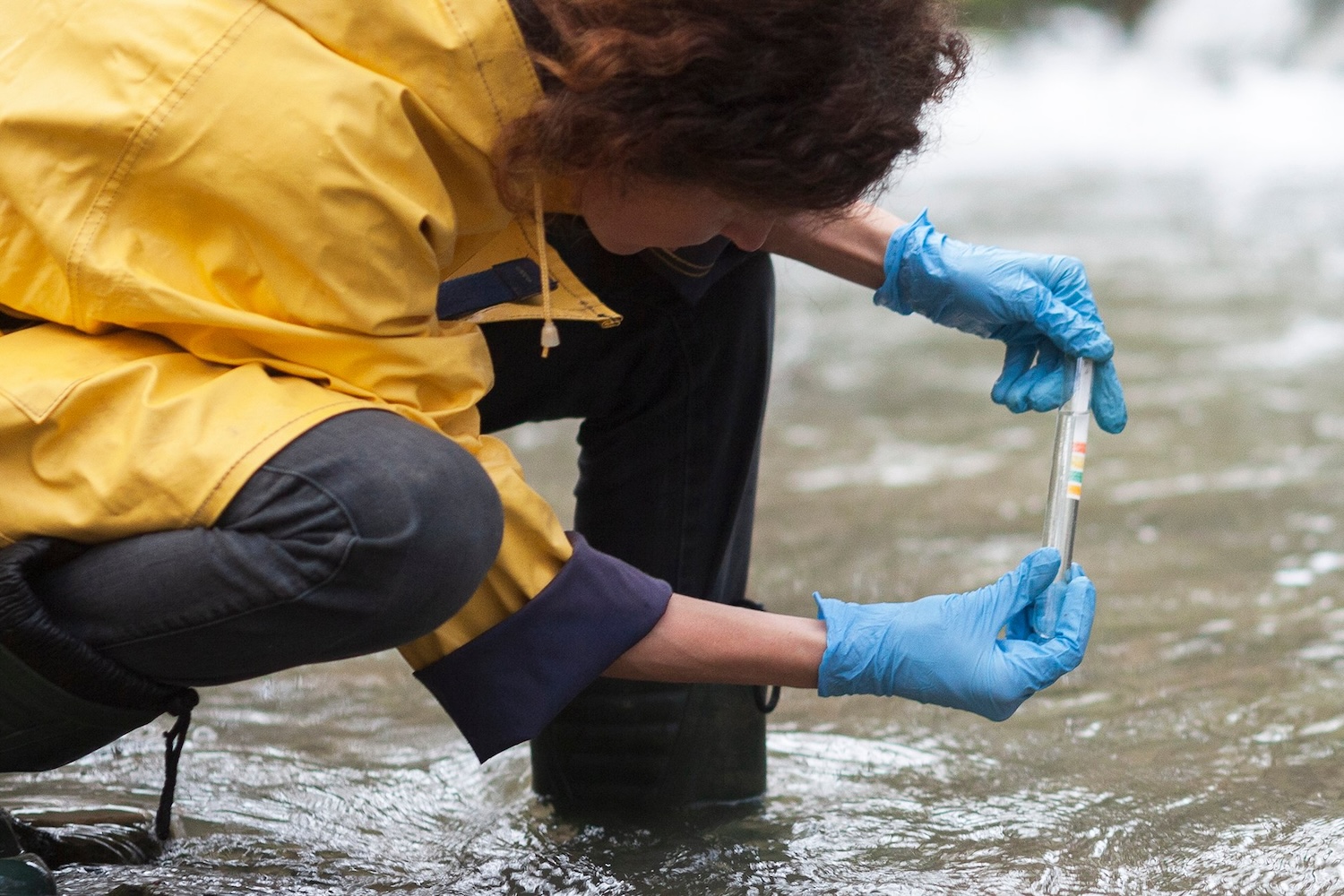 Researcher wearing protective gloves collects a water sample for PFAS testing.