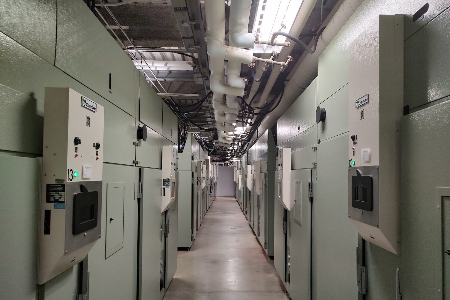 Hallway lined with large controlled-environment growth chambers in a research facility.