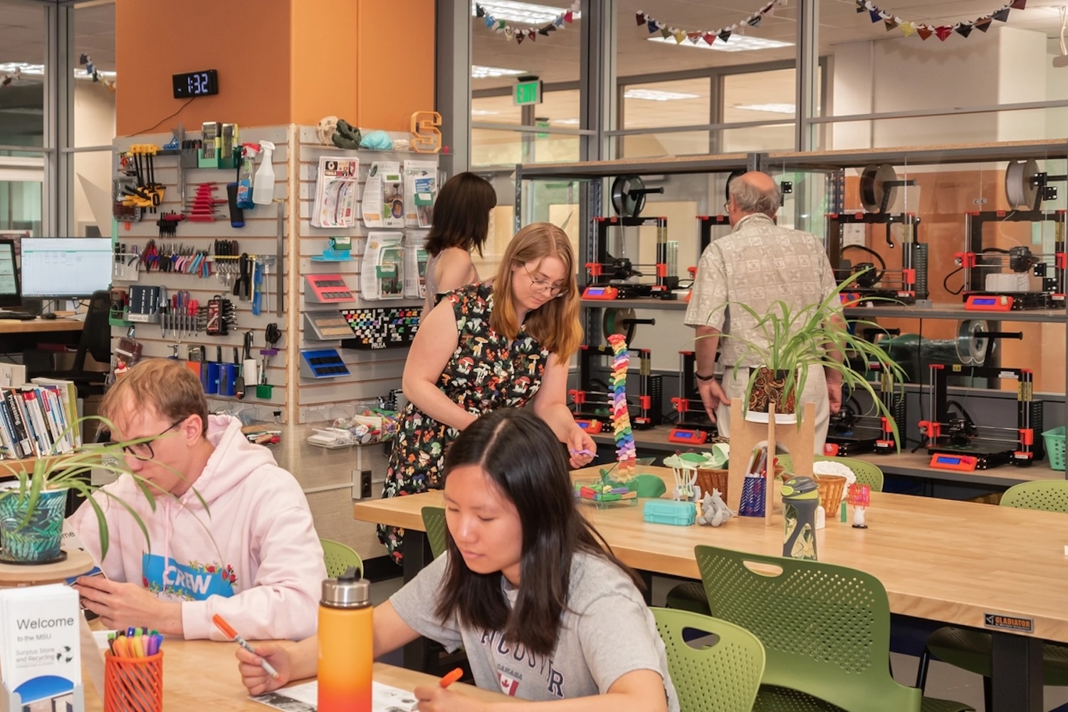 Students and staff work on hands-on projects in the Hollander Makerspace, with 3D printers, tools, supplies, and collaborative work tables visible throughout the room.