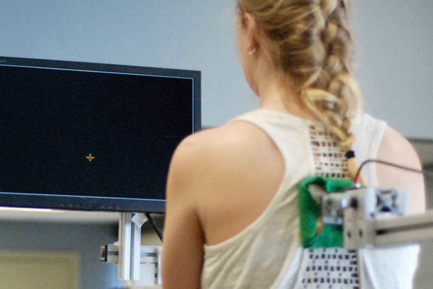 A participant wearing motion-sensing equipment stands in front of a computer display during neuromusculoskeletal research testing.